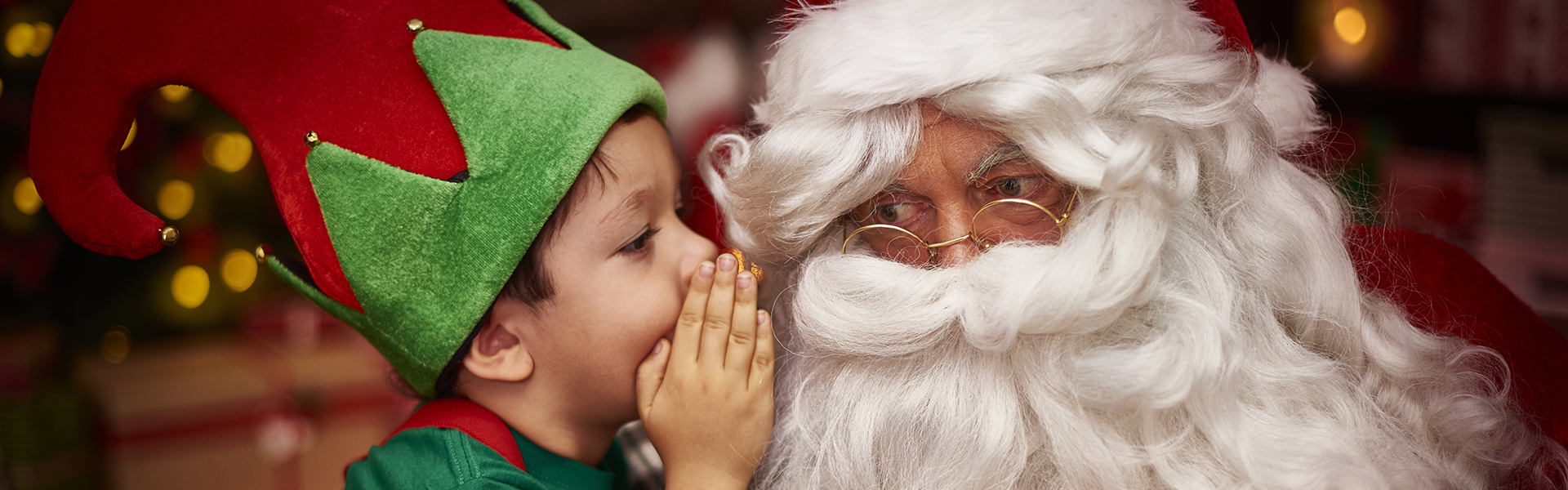 Indicating that email marketing sends the right message at the right time, a cute little boy dressed as elf sits on Santa’s lap and whispers his Christmas gift wish into Santa’s ear.