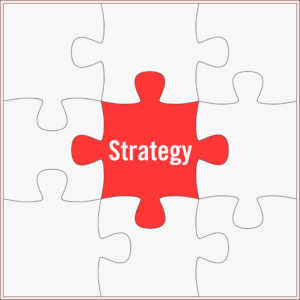 Visual features 9 jigsaw puzzle pieces in a 3 X 3 quadrant. Each puzzle piece is blank except for the red one in the middle names “Strategy,” indicating that strategy must be at the center of it all, whether inbound or outbound marketing.