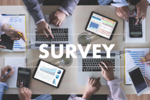 Market research team conducting survey analysis, with people using laptops and digital devices to review data charts and graphs